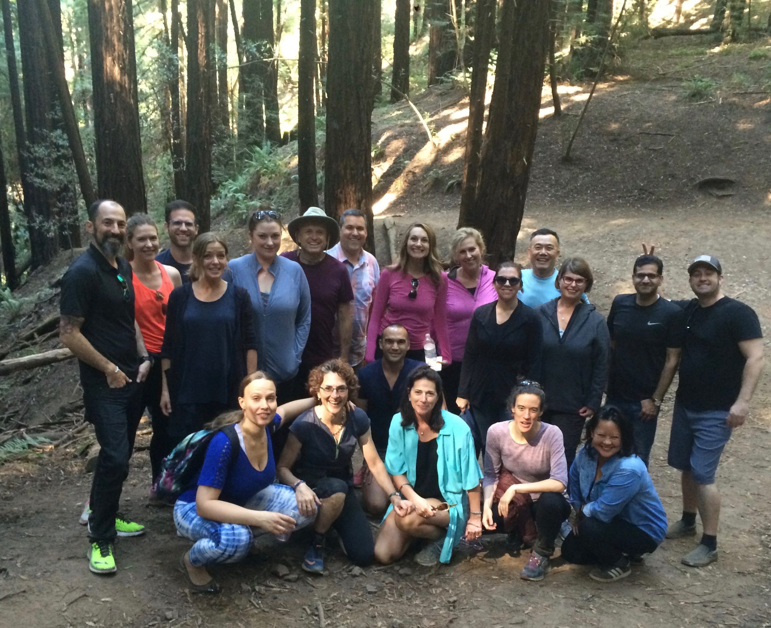 The Schonfield Consulting team cruiches in front of Well Being Trust staffers on a dirt road in a forest