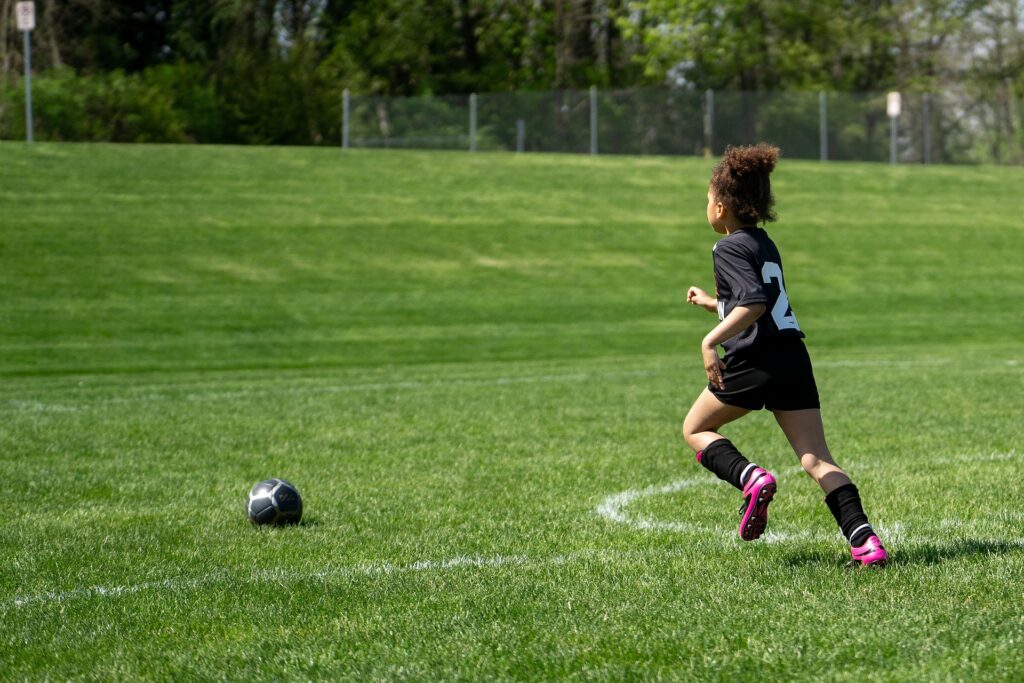 Afrcan American girl playing soccer on a grass playfield